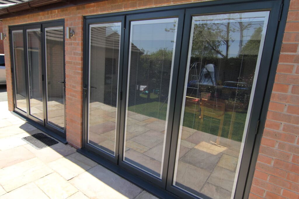 two sets of patio doors having integral blinds in bifold doors on a sunny day